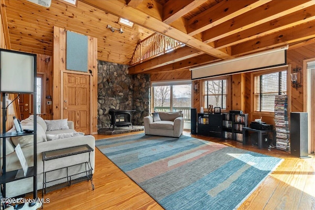 living room featuring a wood stove, light wood-type flooring, wood walls, wooden ceiling, and lofted ceiling with beams