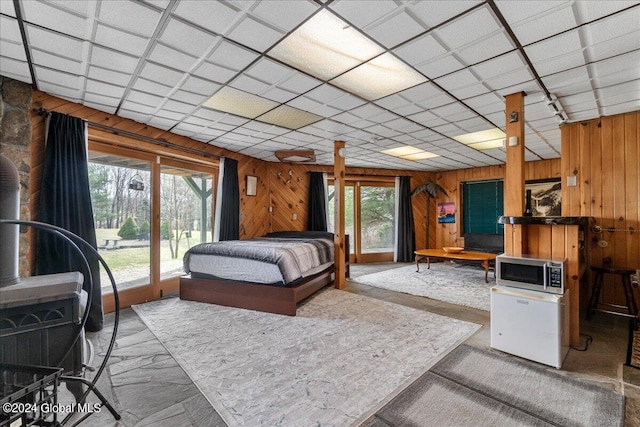 bedroom with a wood stove, wood walls, and access to exterior