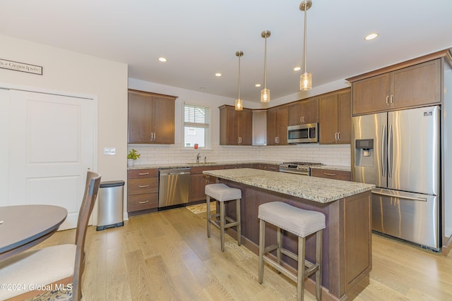 kitchen with a kitchen breakfast bar, light wood-type flooring, appliances with stainless steel finishes, and a center island