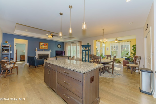 kitchen featuring a raised ceiling, open floor plan, a fireplace, and light wood finished floors