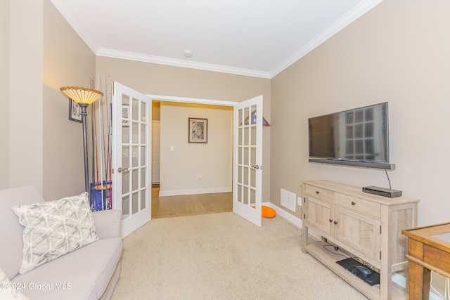 sitting room with crown molding, french doors, visible vents, and light carpet