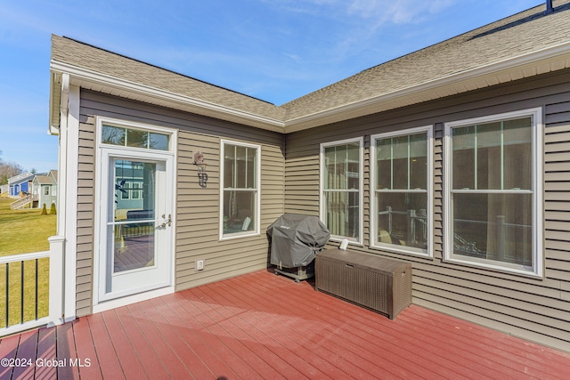 wooden deck featuring a lawn and a grill