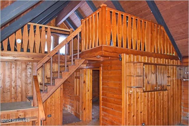 stairway with wooden walls and lofted ceiling