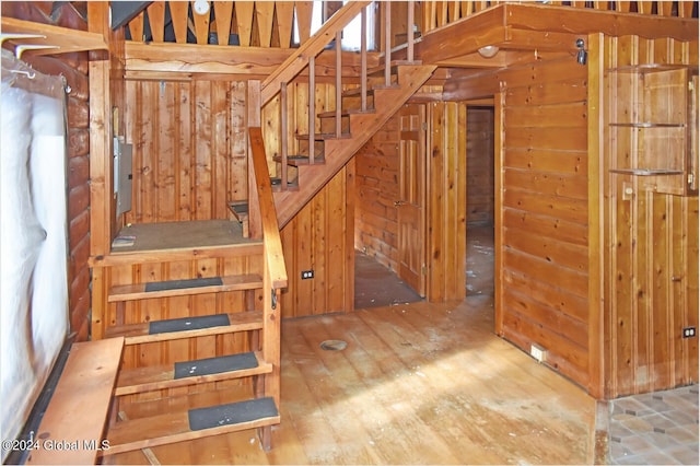 stairs featuring wood walls, hardwood / wood-style floors, and electric panel