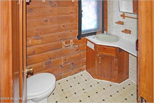 bathroom with tile patterned flooring, wooden walls, toilet, and vanity