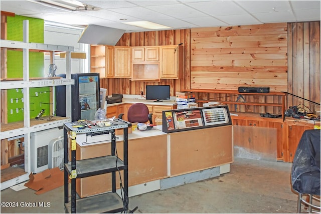 office space with wood walls, concrete flooring, and a paneled ceiling