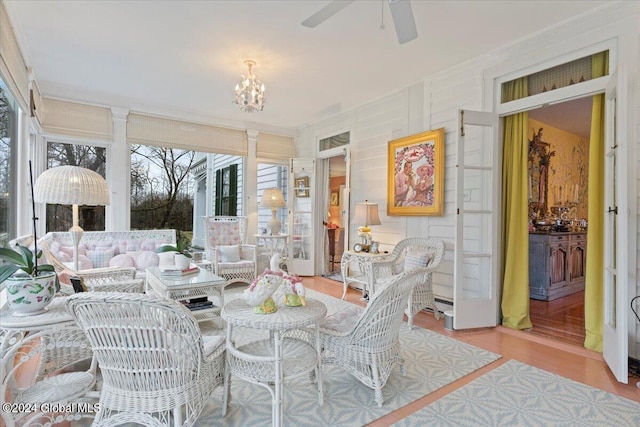 sunroom / solarium featuring decorative columns and ceiling fan with notable chandelier