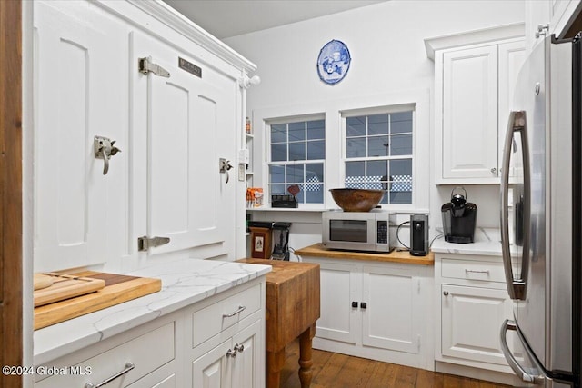 kitchen featuring white cabinets, light hardwood / wood-style flooring, light stone counters, and stainless steel appliances