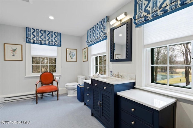 bathroom featuring toilet, a baseboard heating unit, and large vanity