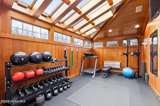 workout area with a skylight, wood walls, and high vaulted ceiling