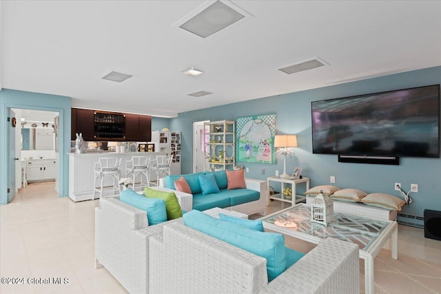 tiled living room featuring baseboard heating and indoor bar