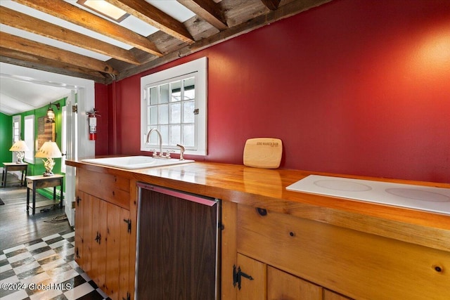 interior space with white electric cooktop, light tile flooring, vaulted ceiling with beams, and sink