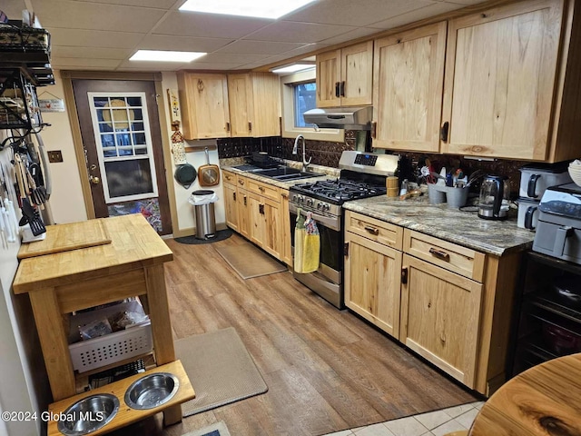 kitchen featuring a drop ceiling, light wood-type flooring, backsplash, sink, and gas stove