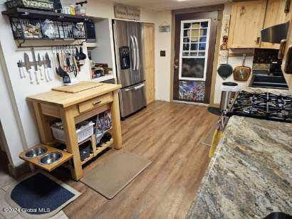 interior space featuring stainless steel fridge with ice dispenser, fume extractor, and light hardwood / wood-style floors