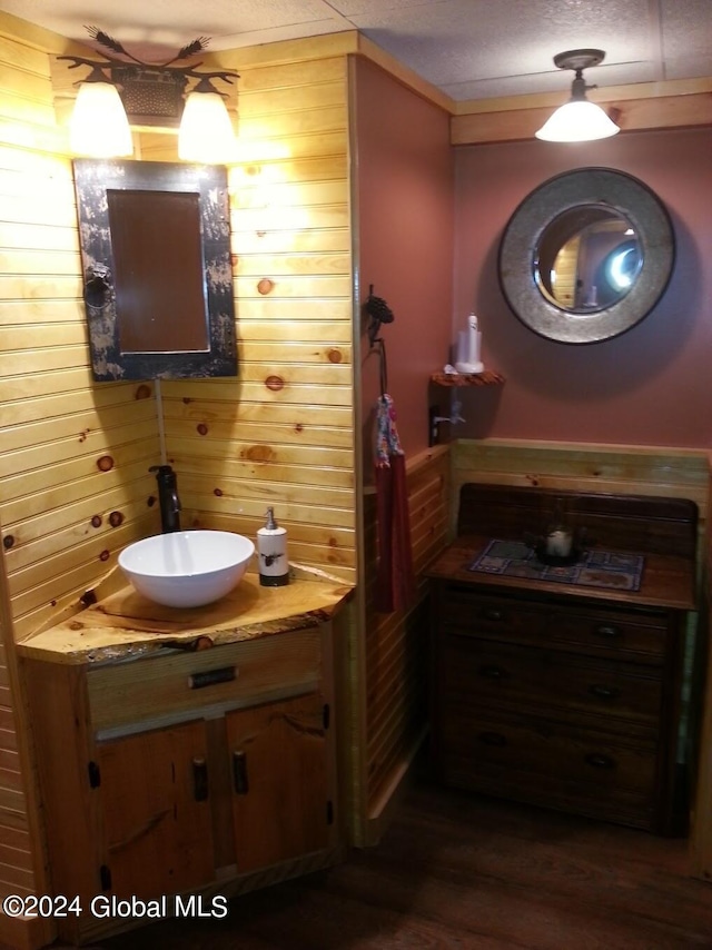 bathroom with wooden walls, hardwood / wood-style flooring, and vanity