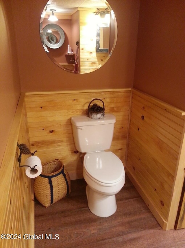 bathroom featuring toilet, wood walls, and hardwood / wood-style floors