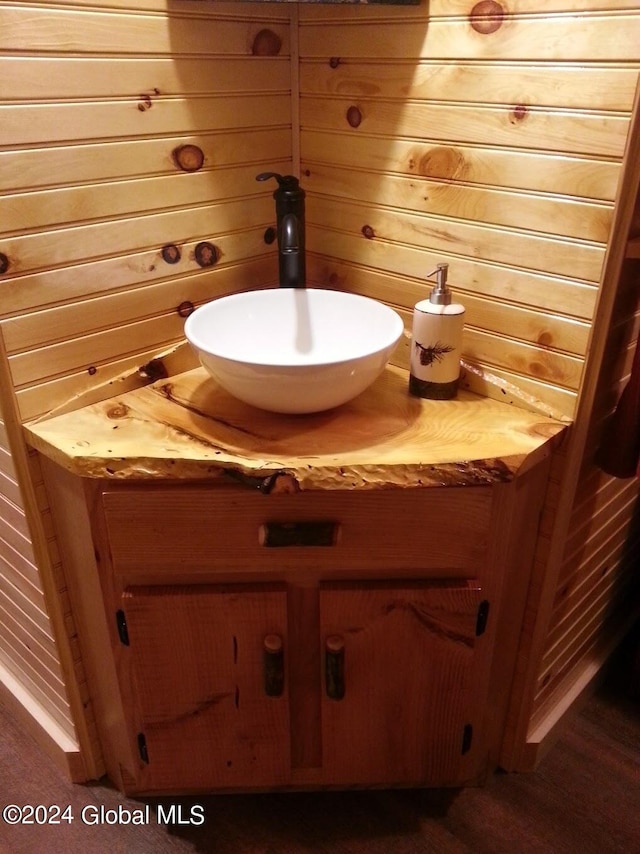 bathroom with hardwood / wood-style flooring, wooden walls, and vanity