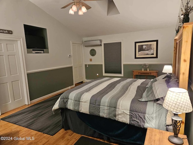 bedroom featuring ceiling fan, lofted ceiling, an AC wall unit, and wood-type flooring