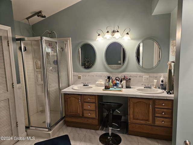 bathroom featuring double sink vanity, tile floors, tasteful backsplash, and a shower with shower door