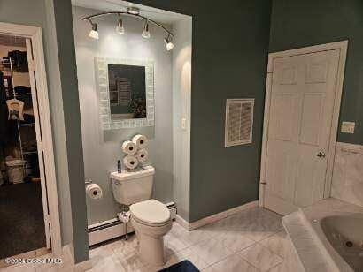 bathroom featuring tile floors, toilet, a baseboard radiator, and a bathing tub