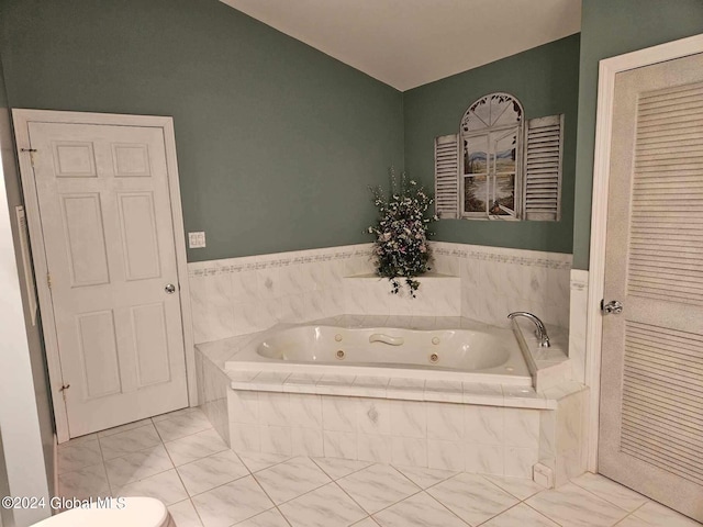 bathroom with tiled bath, tile flooring, and toilet