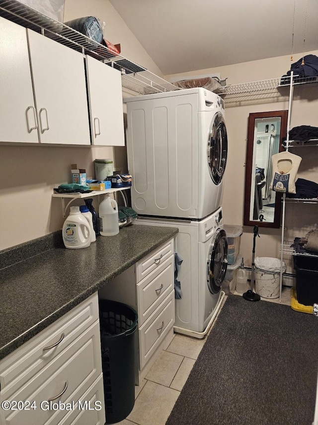 clothes washing area featuring cabinets, stacked washer / drying machine, and light tile floors