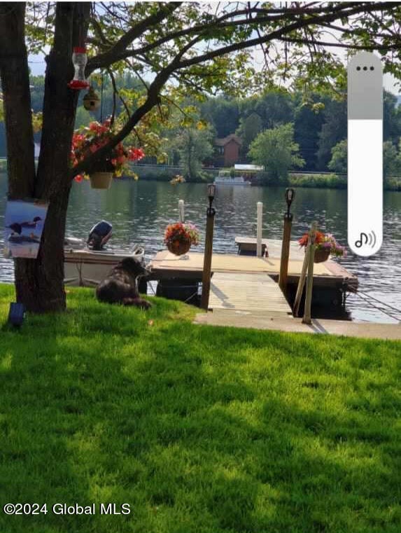 view of dock with a lawn and a water view