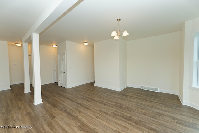 empty room featuring dark wood-type flooring and an inviting chandelier