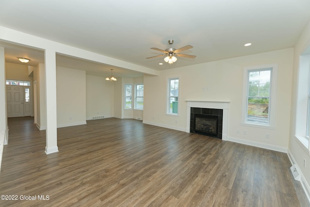 unfurnished living room with dark hardwood / wood-style flooring, ceiling fan with notable chandelier, and a fireplace