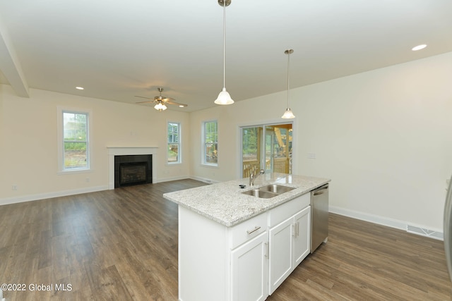 kitchen featuring sink, light stone counters, decorative light fixtures, stainless steel dishwasher, and a kitchen island with sink