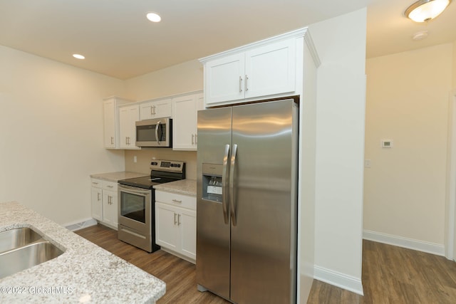 kitchen featuring white cabinetry, stainless steel appliances, dark wood-type flooring, and light stone counters