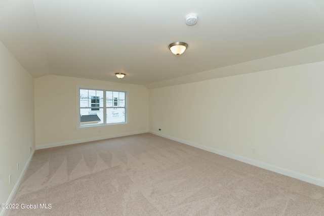 carpeted spare room featuring lofted ceiling