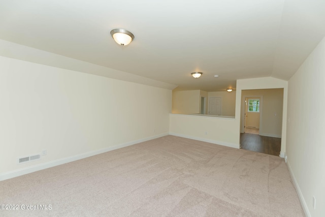 carpeted empty room featuring lofted ceiling