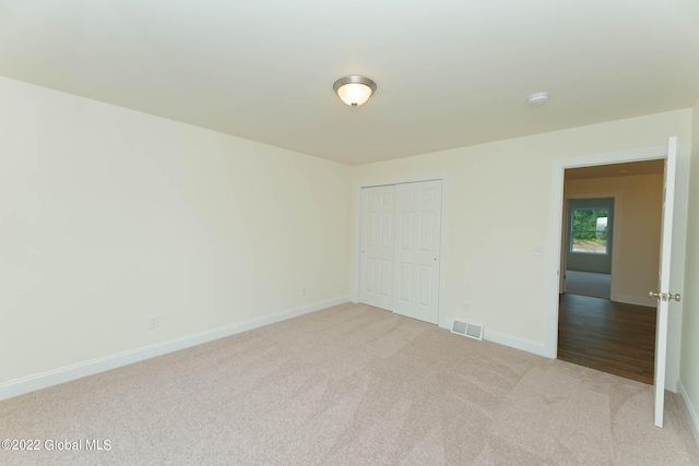 unfurnished bedroom with light carpet and a closet