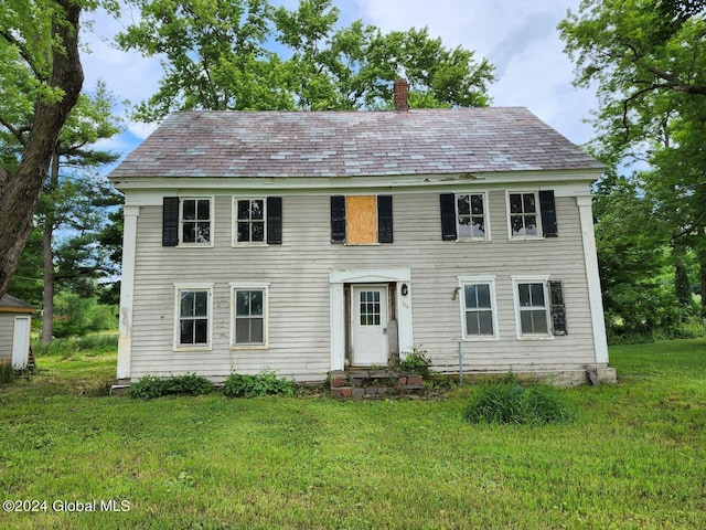 colonial-style house featuring a front lawn