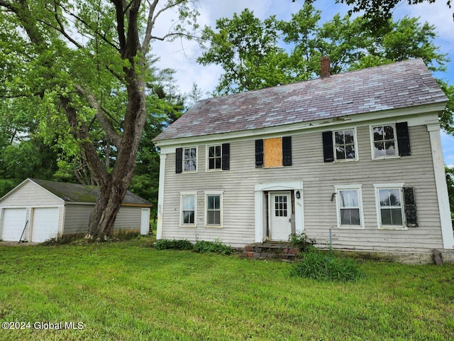 colonial-style house with a front lawn, a garage, and an outdoor structure