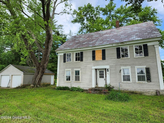 colonial-style house with a garage, an outdoor structure, and a front lawn