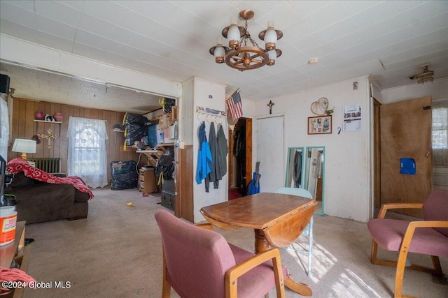 carpeted dining room with a notable chandelier and wood walls