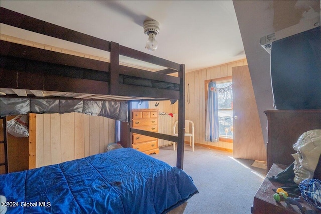 carpeted bedroom featuring wooden walls