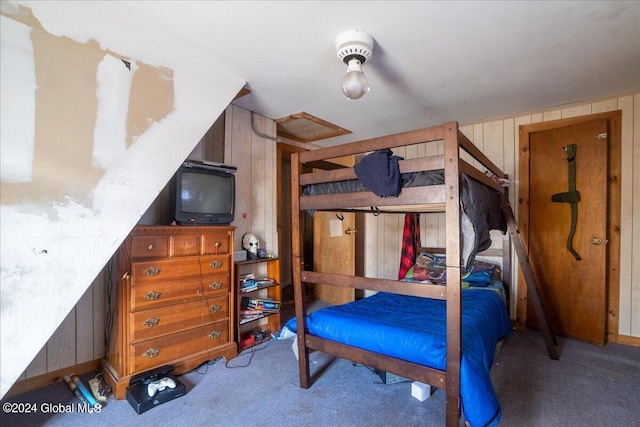 bedroom featuring wood walls and dark colored carpet