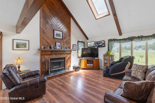 living room with a skylight, a fireplace, high vaulted ceiling, hardwood / wood-style floors, and wood walls