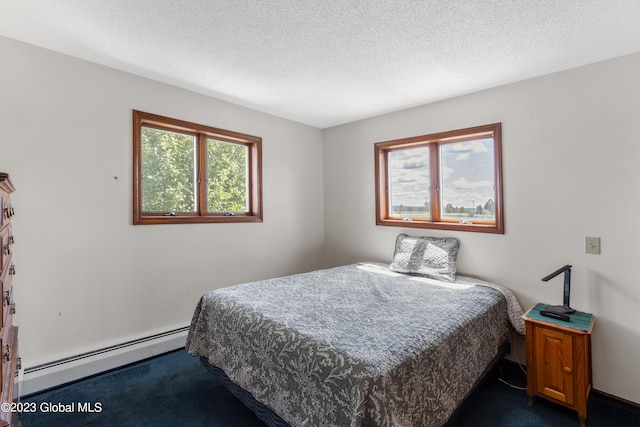 carpeted bedroom with baseboard heating and a textured ceiling