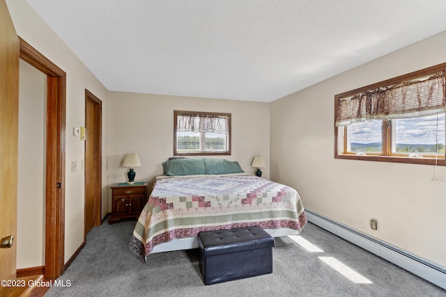 carpeted bedroom featuring a textured ceiling and a baseboard heating unit