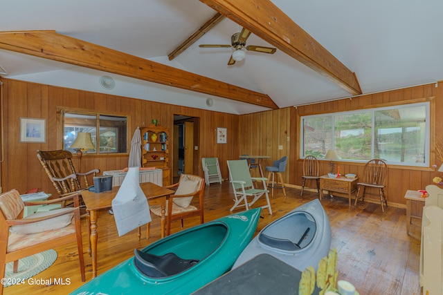 interior space with lofted ceiling with beams, ceiling fan, wood walls, and hardwood / wood-style floors