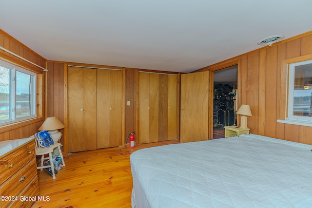 bedroom with light hardwood / wood-style floors and wooden walls