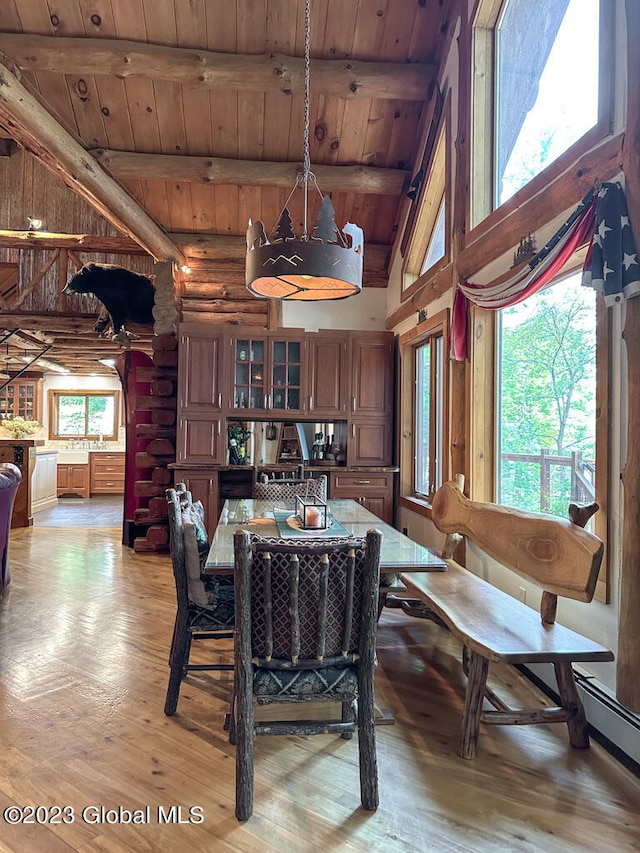 dining space featuring log walls, beamed ceiling, light hardwood / wood-style floors, and wooden ceiling