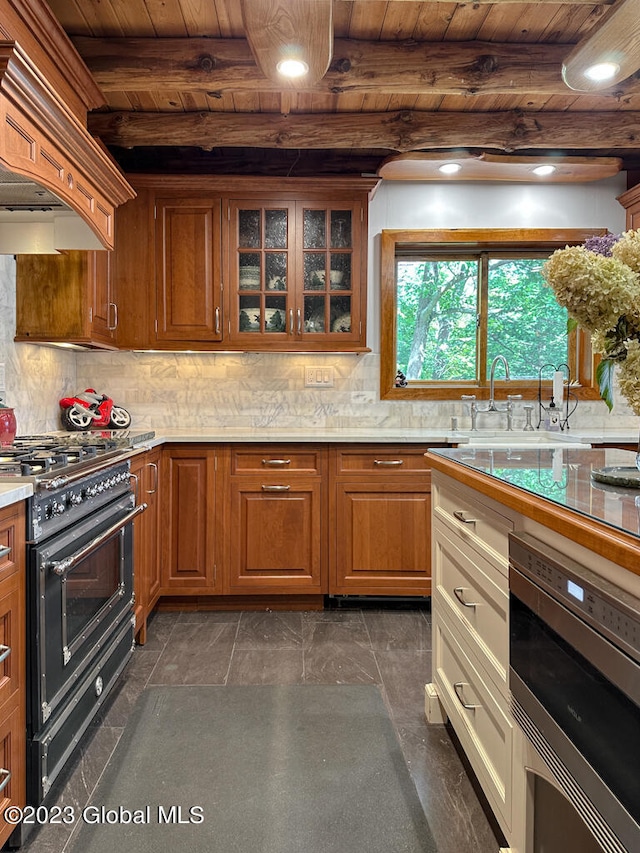 kitchen with beamed ceiling, tasteful backsplash, range with two ovens, and stainless steel oven