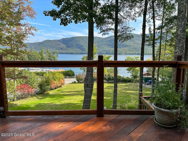 deck with a water and mountain view and a lawn