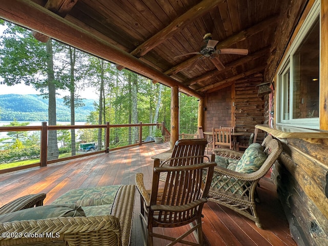 sunroom featuring ceiling fan, lofted ceiling with beams, wood ceiling, and a mountain view