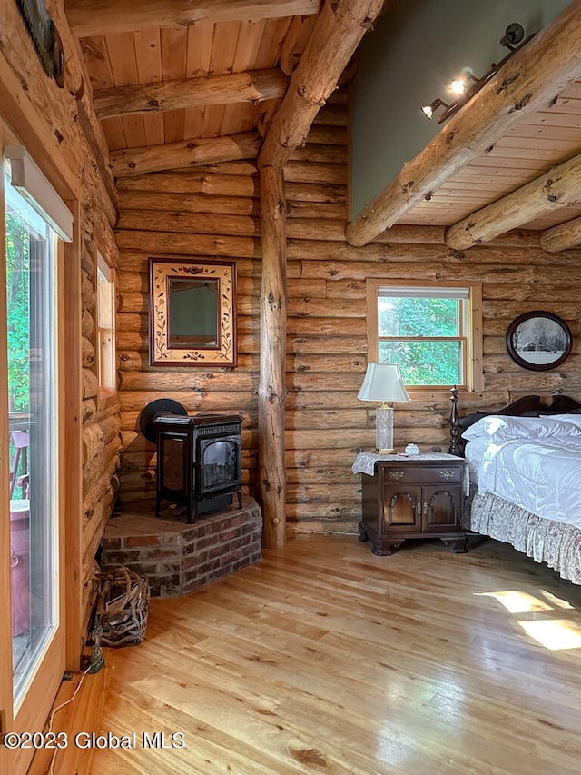 bedroom with log walls, vaulted ceiling with beams, hardwood / wood-style floors, and a wood stove